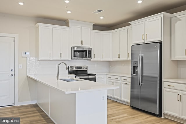 kitchen with light wood finished floors, light countertops, appliances with stainless steel finishes, and white cabinets