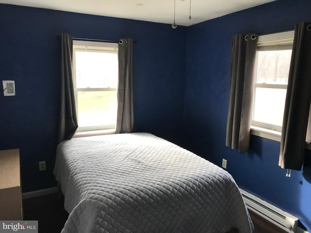 bedroom featuring multiple windows and a baseboard heating unit