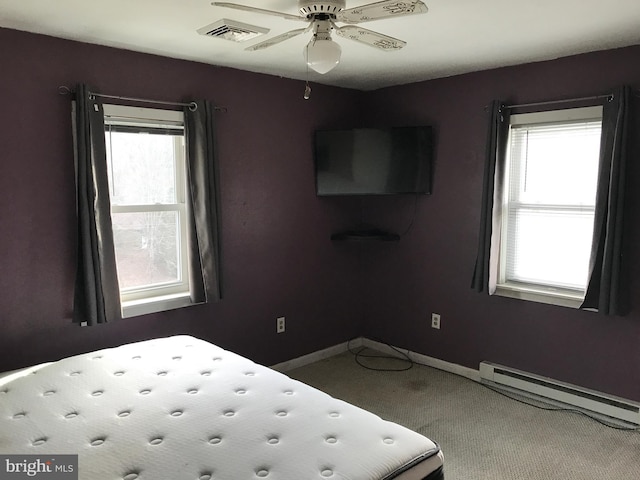 unfurnished bedroom with multiple windows, ceiling fan, carpet, and baseboard heating