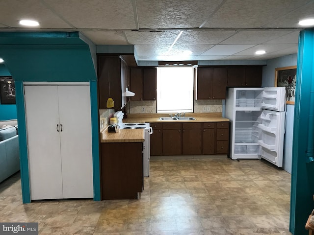 kitchen featuring dark brown cabinetry, sink, a paneled ceiling, fridge, and white range with electric cooktop