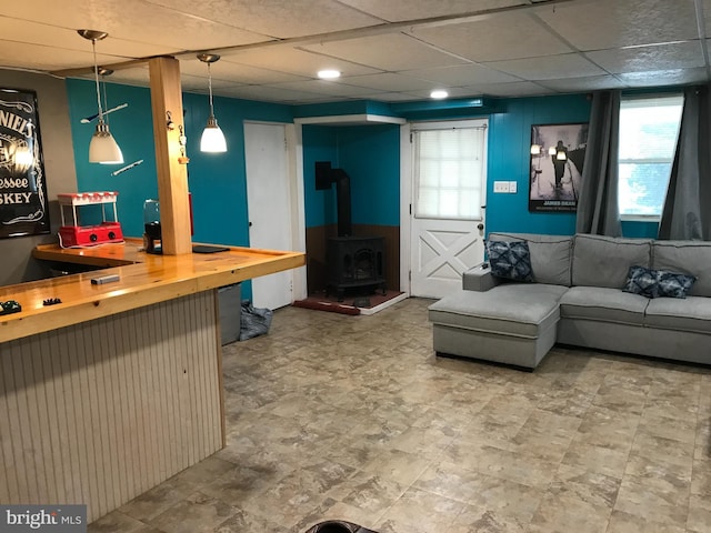 living room with a paneled ceiling and a wood stove