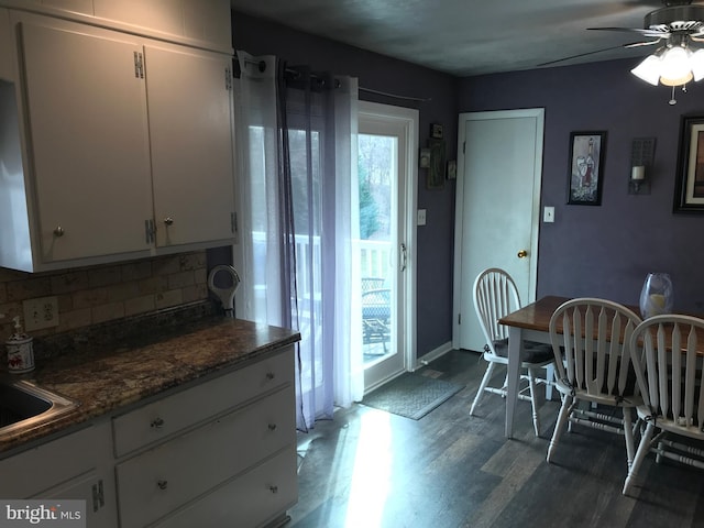 kitchen with ceiling fan, white cabinetry, wood-type flooring, decorative backsplash, and dark stone counters