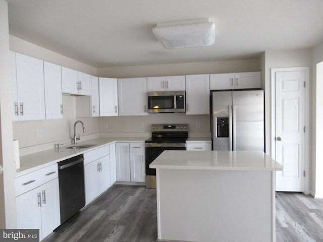 kitchen with sink, stainless steel appliances, a center island, white cabinets, and dark hardwood / wood-style flooring