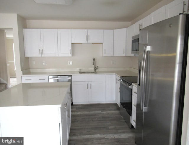 kitchen featuring appliances with stainless steel finishes, white cabinetry, sink, light stone countertops, and dark wood-type flooring