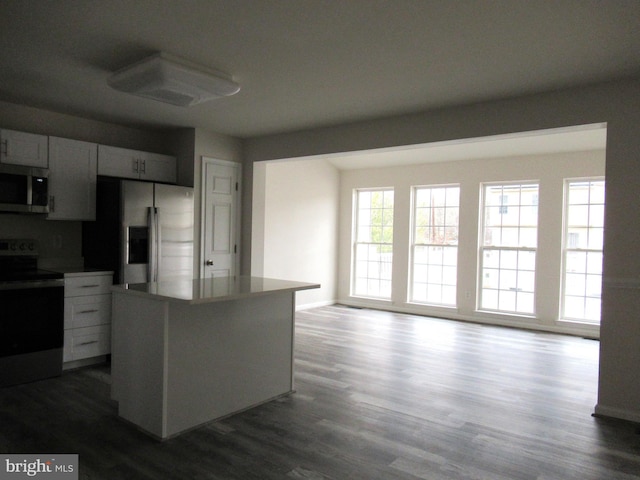 kitchen with stainless steel appliances, dark hardwood / wood-style flooring, a kitchen island, and white cabinets