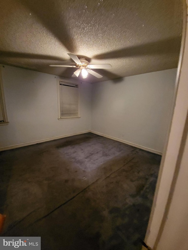 spare room with ceiling fan, a textured ceiling, and dark colored carpet