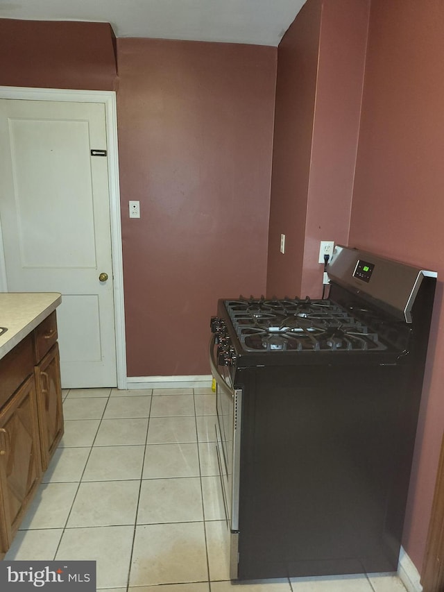 kitchen with stainless steel gas stove and light tile patterned flooring