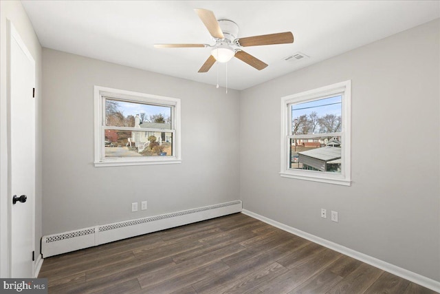 empty room featuring baseboards, visible vents, dark wood finished floors, and baseboard heating