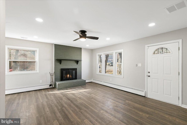 unfurnished living room featuring a baseboard radiator, dark wood finished floors, visible vents, and a brick fireplace