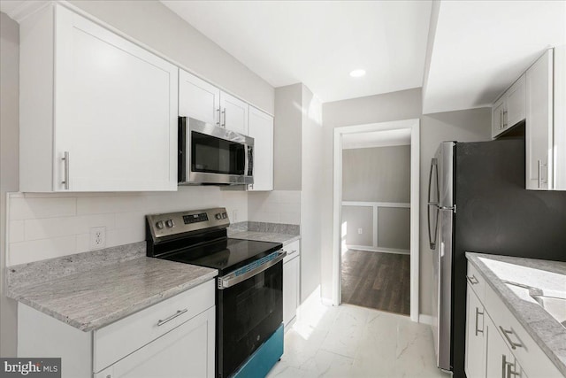 kitchen featuring light stone counters, marble finish floor, stainless steel appliances, tasteful backsplash, and white cabinets