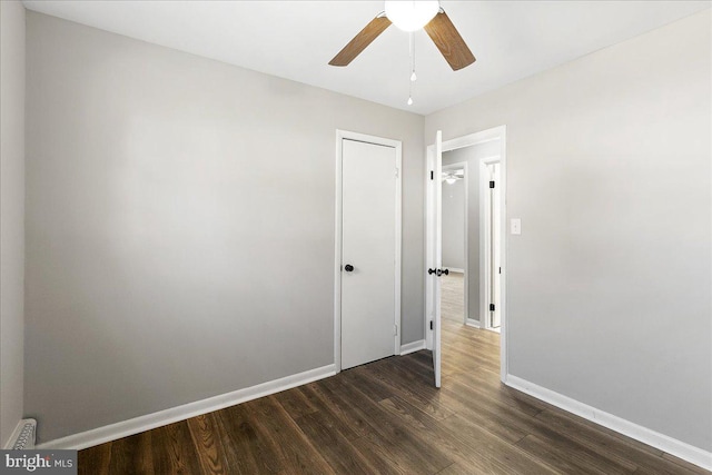 unfurnished bedroom with dark wood-style flooring, a ceiling fan, and baseboards