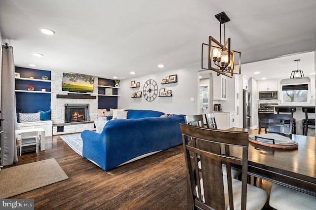 living room featuring dark hardwood / wood-style floors, a chandelier, built in features, and a fireplace