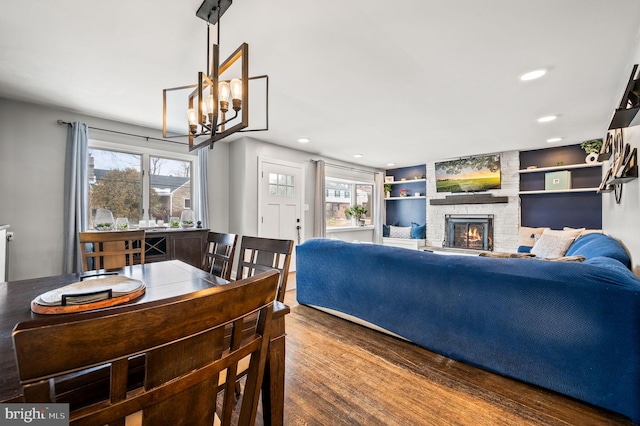 dining room with hardwood / wood-style flooring, a stone fireplace, and built in features