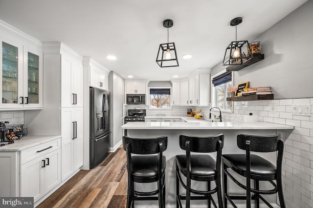 kitchen with stainless steel appliances, white cabinetry, pendant lighting, and kitchen peninsula