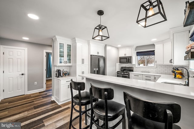 kitchen featuring dark wood-type flooring, sink, appliances with stainless steel finishes, pendant lighting, and white cabinets