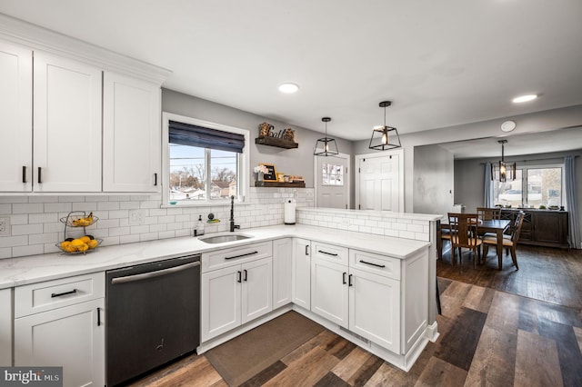 kitchen with sink, dishwasher, hanging light fixtures, white cabinets, and kitchen peninsula