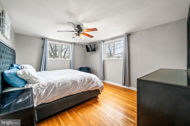 bedroom featuring multiple windows, wood-type flooring, and ceiling fan