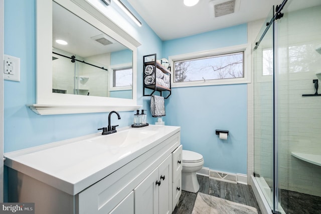 bathroom with a shower with door, vanity, wood-type flooring, and toilet