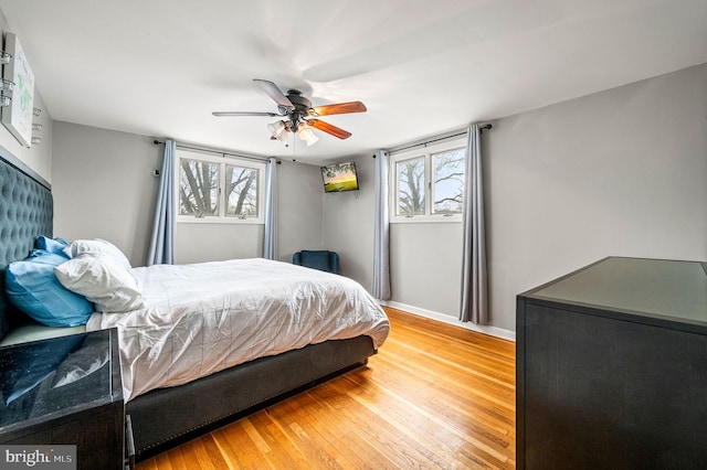 bedroom with ceiling fan, wood-type flooring, and multiple windows