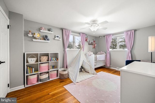 bedroom with hardwood / wood-style flooring, ceiling fan, and multiple windows