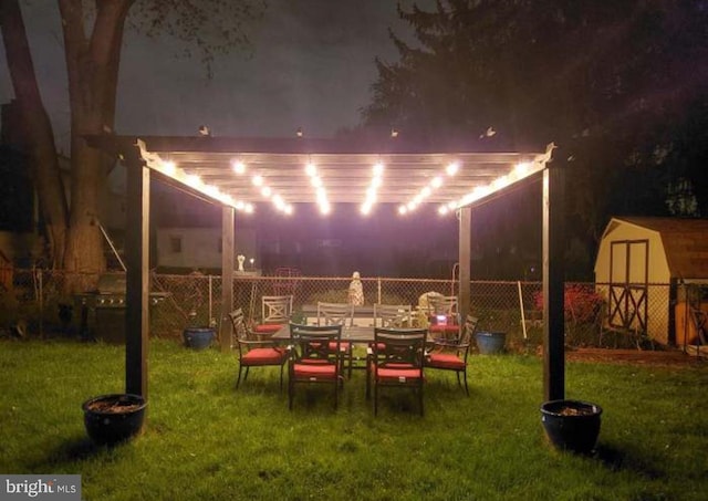 yard at night featuring a storage shed and a pergola