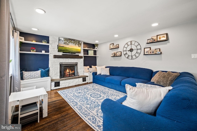 living room with a stone fireplace, dark hardwood / wood-style floors, and built in features