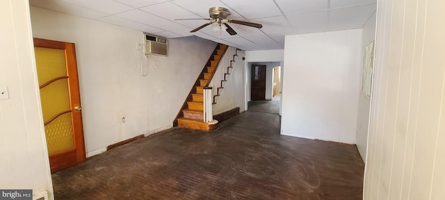 basement featuring ceiling fan, a wall mounted air conditioner, and a drop ceiling