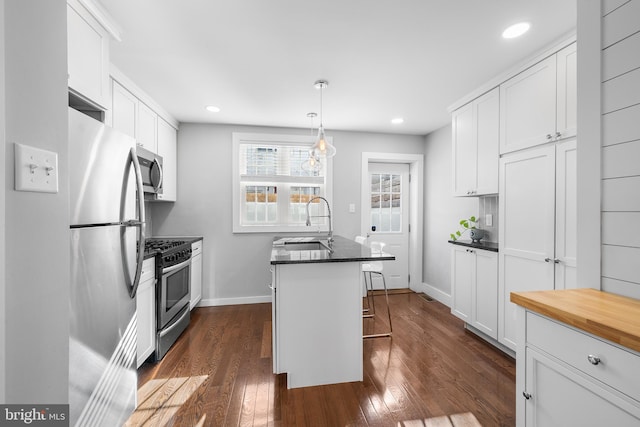 kitchen with stainless steel appliances, white cabinetry, a breakfast bar area, and a center island with sink