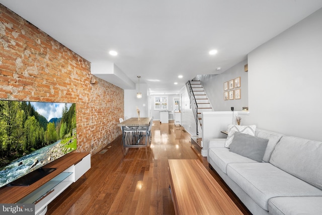 unfurnished living room featuring wood-type flooring and brick wall