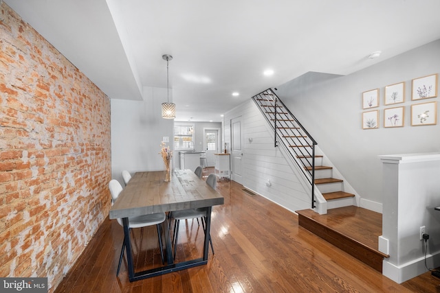 dining space featuring brick wall and dark hardwood / wood-style floors