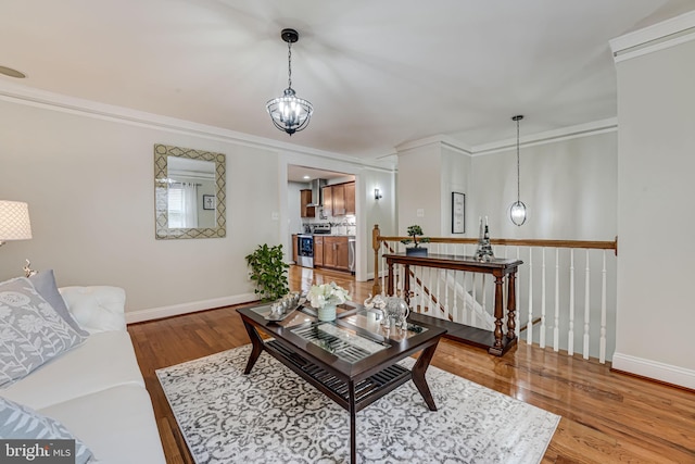 living room with a notable chandelier, ornamental molding, and light hardwood / wood-style floors