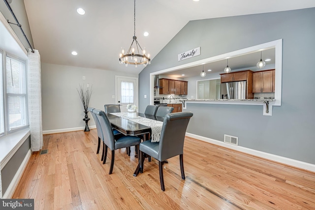 dining room with light hardwood / wood-style flooring, a chandelier, and vaulted ceiling