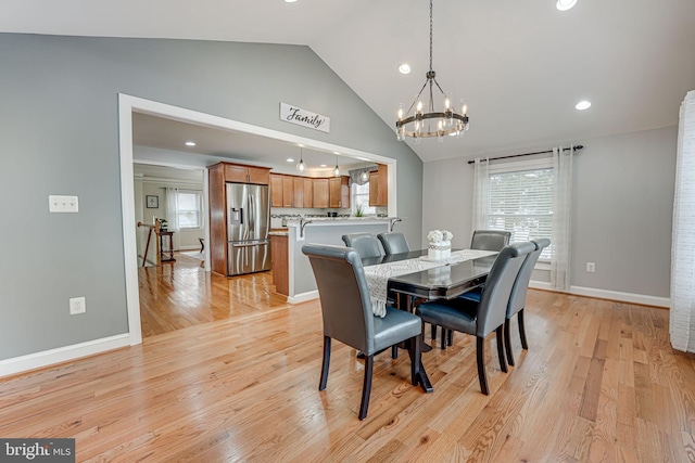 dining room with a wealth of natural light, light hardwood / wood-style floors, and vaulted ceiling