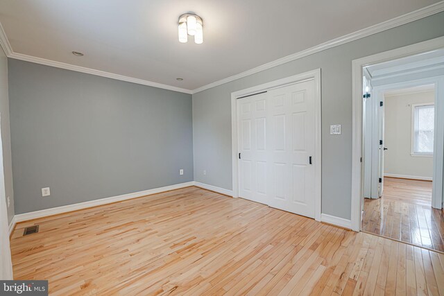 unfurnished bedroom featuring ornamental molding, light wood-type flooring, and a closet