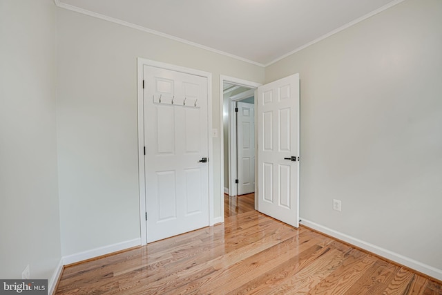 spare room featuring crown molding and light hardwood / wood-style floors