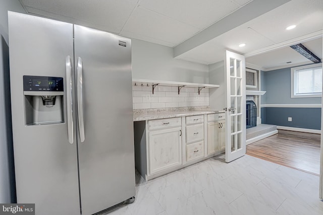 kitchen with white cabinets, stainless steel fridge, and backsplash