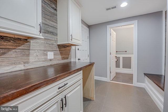 kitchen featuring decorative backsplash, wooden counters, and white cabinets