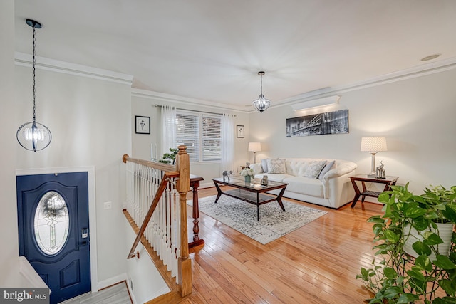 living room with a notable chandelier, crown molding, and light wood-type flooring