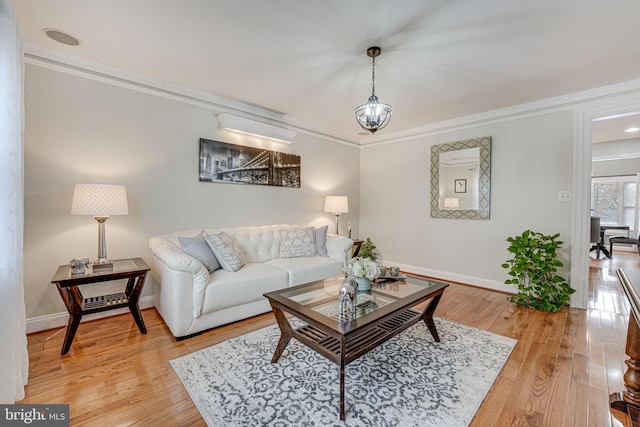 living room featuring an inviting chandelier, wood-type flooring, and ornamental molding