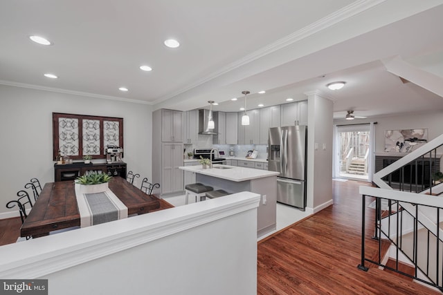 kitchen featuring sink, gray cabinets, stainless steel refrigerator with ice dispenser, a center island with sink, and wall chimney exhaust hood