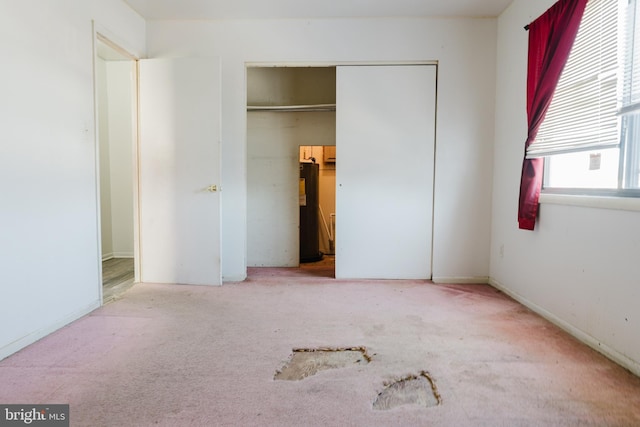 unfurnished bedroom featuring water heater, carpet, and a closet