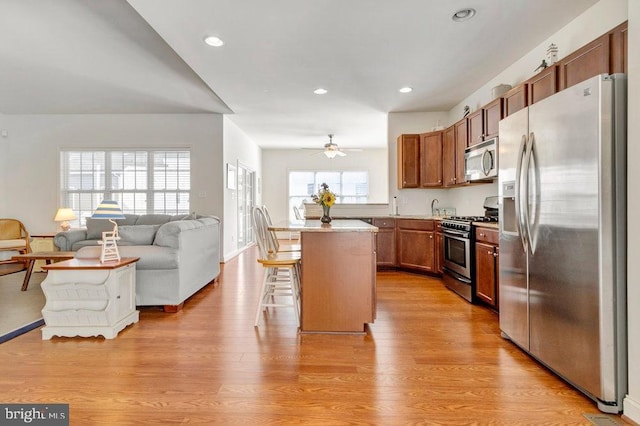 kitchen with stainless steel appliances, a center island, a breakfast bar, and light wood-type flooring