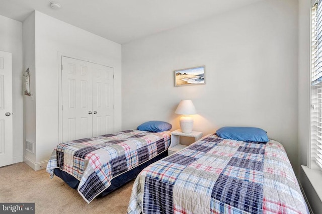 bedroom with light carpet and a closet