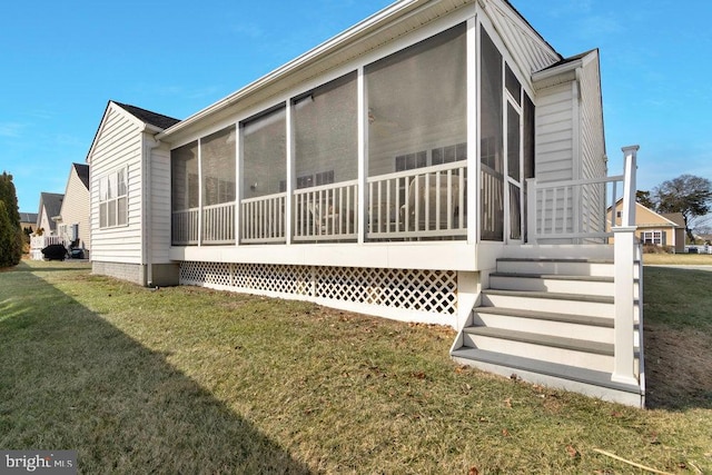 view of side of home featuring a sunroom and a lawn