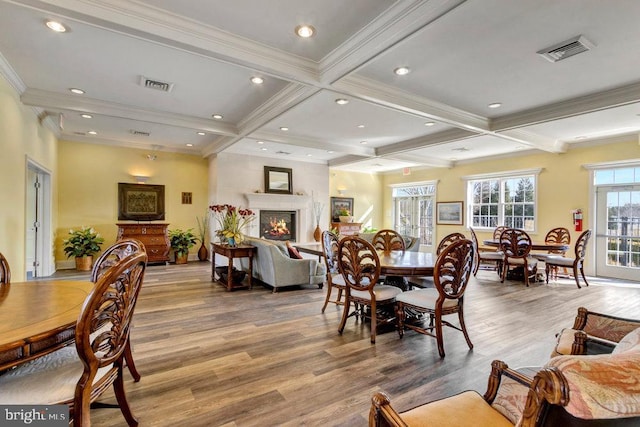 dining space with coffered ceiling, light hardwood / wood-style flooring, and beamed ceiling