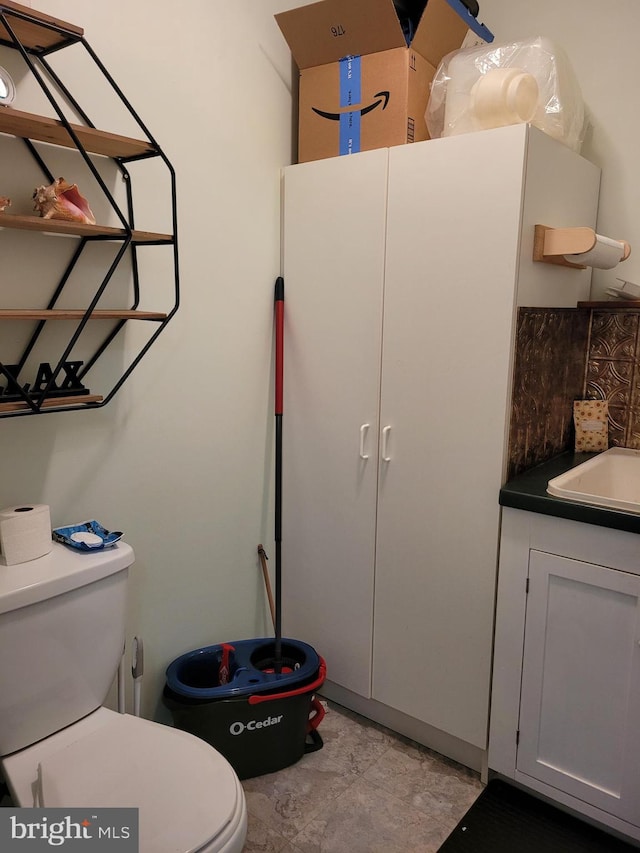 bathroom featuring vanity, toilet, and backsplash