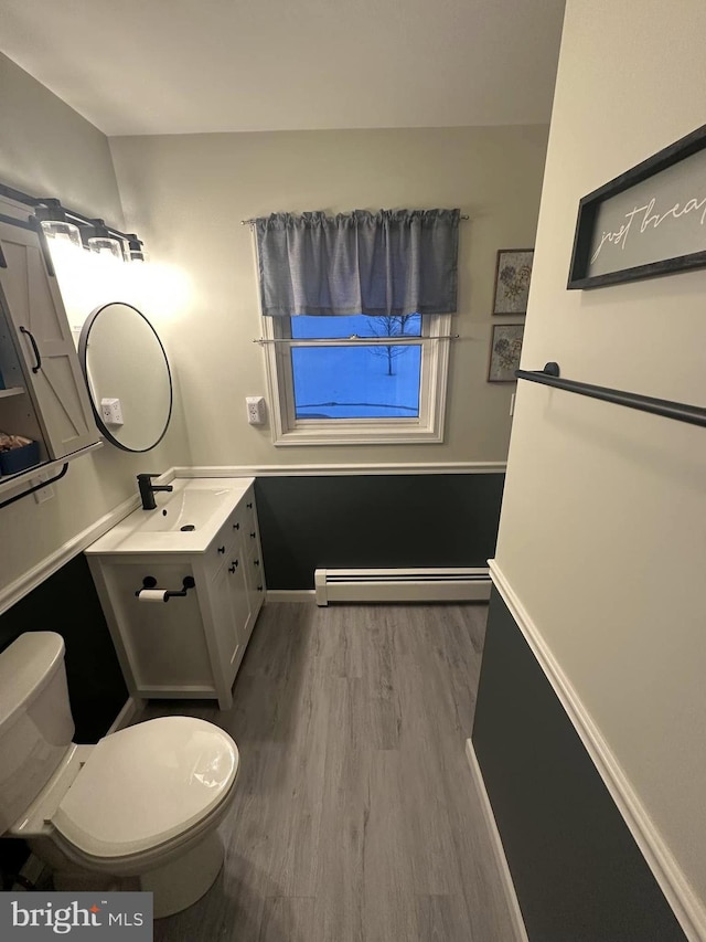 bathroom with vanity, hardwood / wood-style floors, a baseboard radiator, and toilet