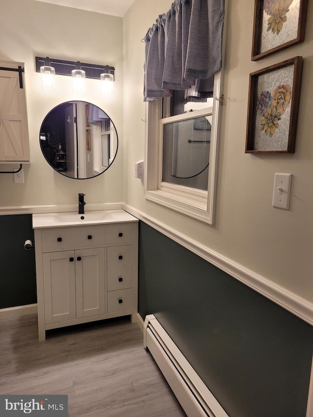 bathroom with hardwood / wood-style flooring, vanity, and a baseboard heating unit