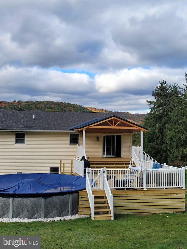 rear view of property with a swimming pool side deck and a lawn