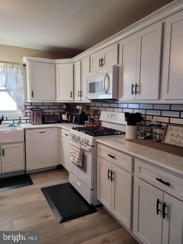 kitchen featuring white cabinetry, white appliances, tasteful backsplash, and light hardwood / wood-style flooring